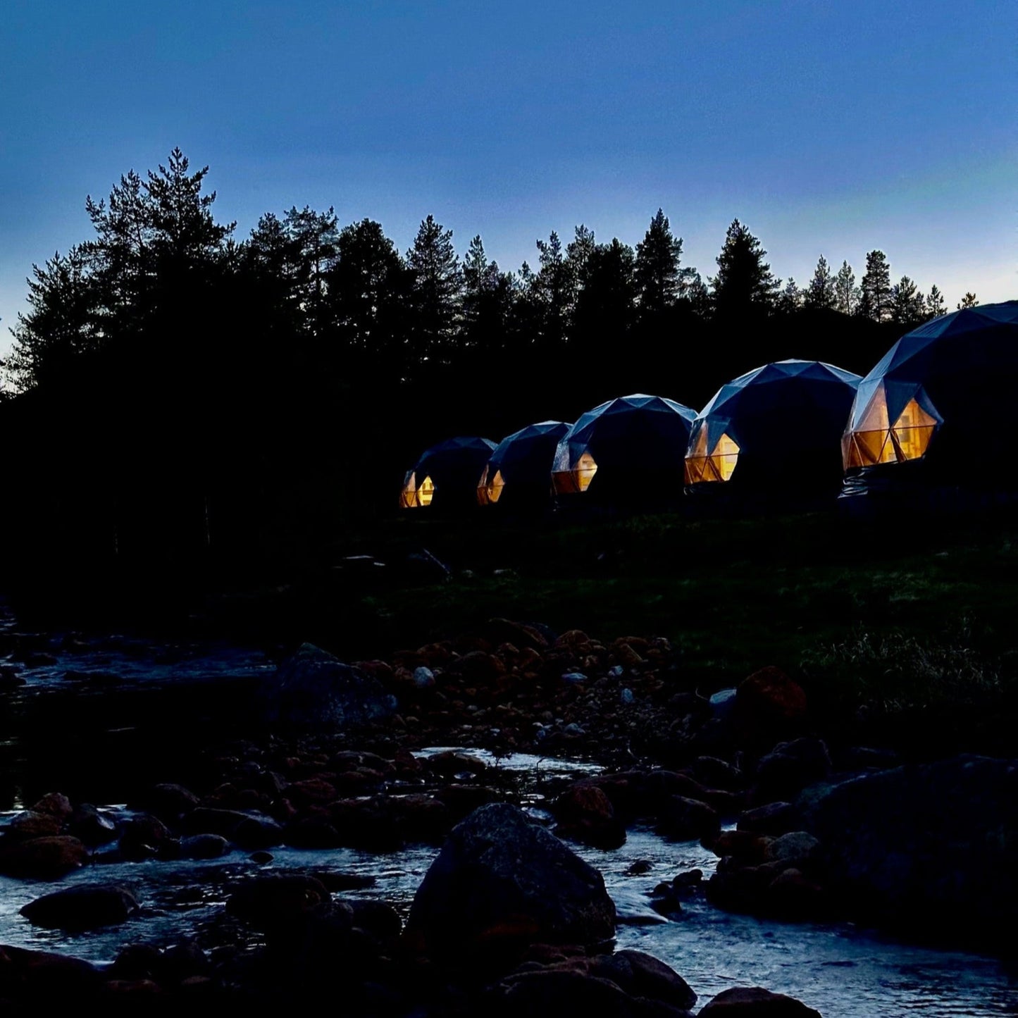 Eco-lux domer på kvelden med lys, utsikt over elven